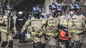 Firefighters evacuating an injured person on a stretcher from an accident site